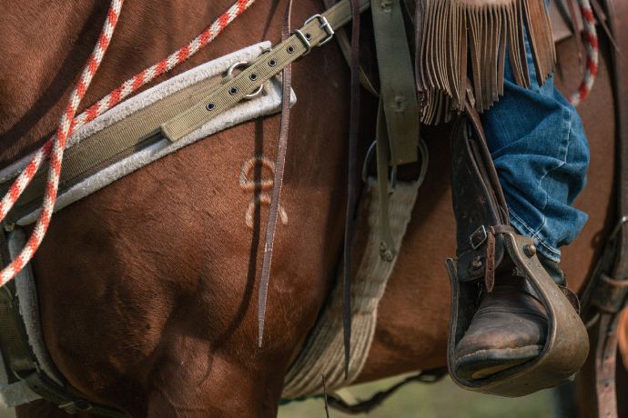 A tight photograph of a person on a horse detailing an Ariat boot in a horse stirrup