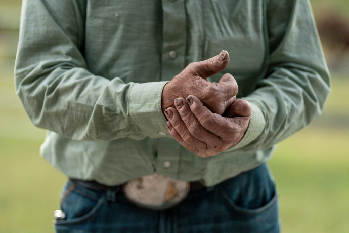 A tight photograph of a person in cowboy attire wringing their hands