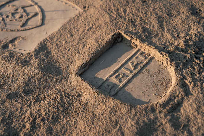 A photograph of a boot print in the sand that shows the Ariat logo