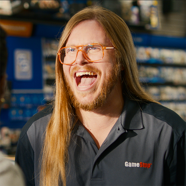 A still frame from a commercial McGarrah Jessee made for GameStop. In the still we see a GameStop associate with long hair and glasses laughing.