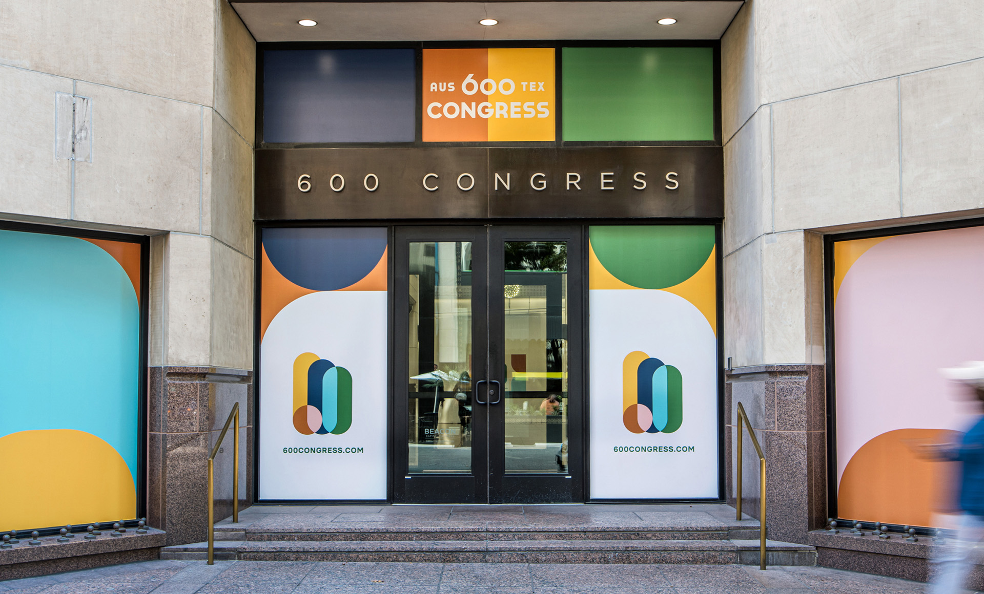 Photo of the window cling designs on the 600 Congress building including the logo and branding