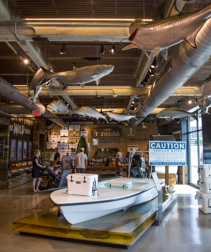 An interior photo of the YETI Flagship store experience including a shallow water boat filled with YETIs